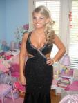 Fair skinned blonde high school student in a black and silver dress that has side cutouts and a deep neckline. that shows her cleavage